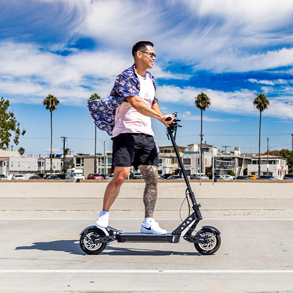 Man riding scooter on beach boardwalk smiling on a sunny day