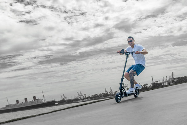 man crouching while riding electric scooter on a foggy day next to harbor